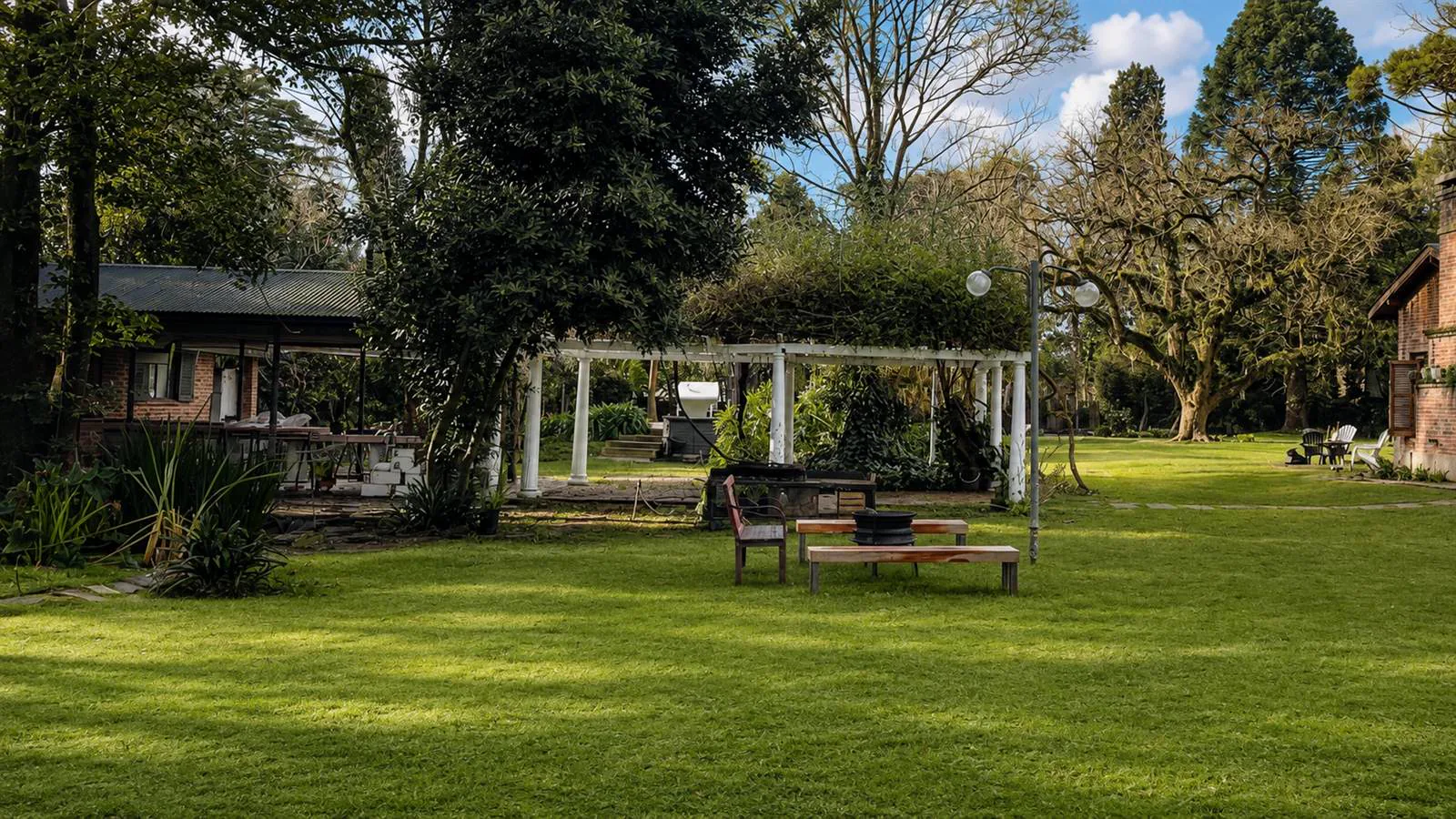 Living exterior junto a pérgola y fogonero encendido en el parque de Sendero Leloir