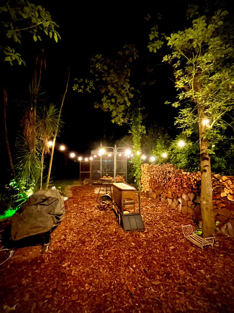 Quincho de noche iluminado con leña apilada en Sendero Leloir