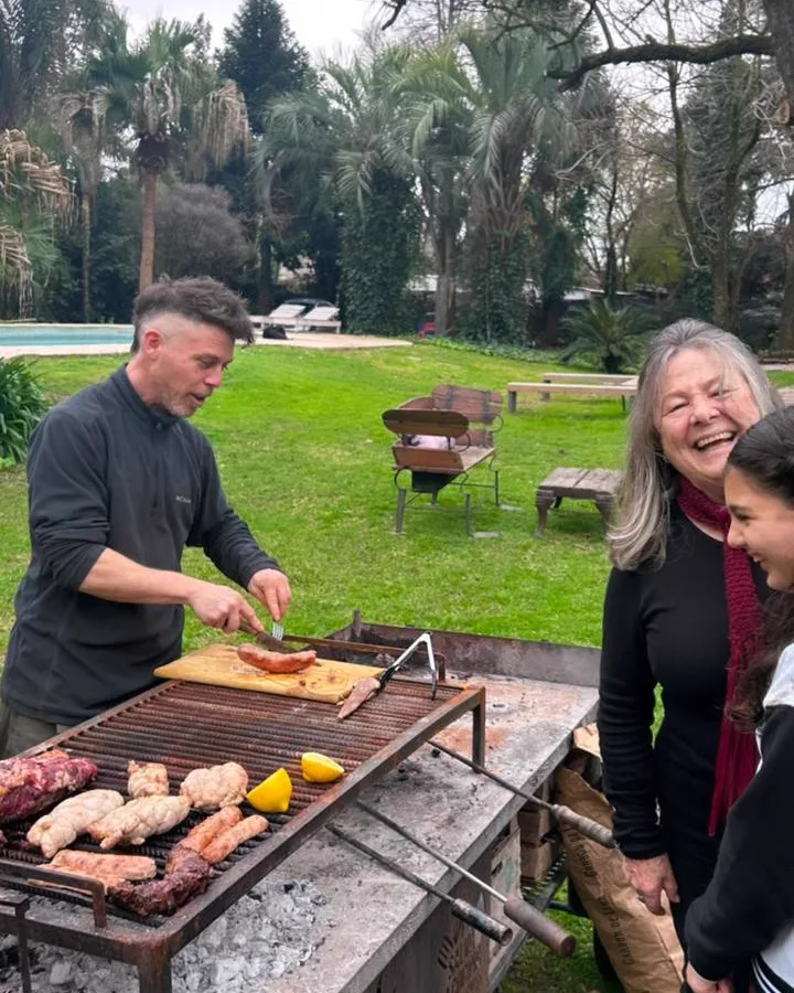 Hernán atendiendo la parrilla junto a invitados en Sendero Leloir