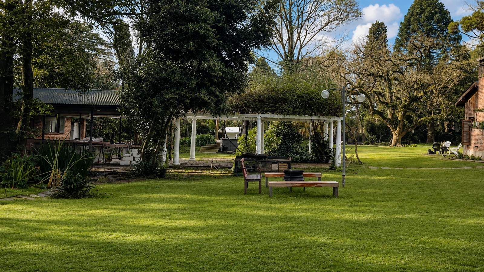 Living exterior junto a pérgola y fogonero encendido en el parque de Sendero Leloir
